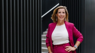 Louisa Böhringer im pinkfarbenen Hosenanzug vor moderner Architektur mit schwarzer Fassade.