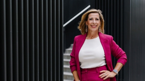 Louisa Böhringer im pinkfarbenen Hosenanzug vor moderner Architektur mit schwarzer Fassade.